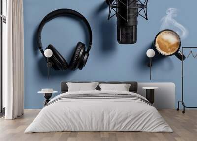 A flat lay, top-down view of a music or podcast setup on a blue table. Black headphones rest next to a sleek recording microphone, a steaming cup of coffee, and an open laptop. Wall mural