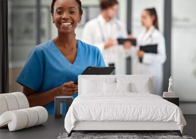 Portrait of happy woman doctor working on a digital tablet and smile while working at a hospital. Black female nurse doing medical and healthcare research on the internet or online at work at clinic Wall mural