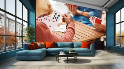 Senior friends, hands or playing card games on wooden table in fun activity, social bonding or gathering. Group of elderly men having fun with cards for poker game enjoying play time together at home Wall mural