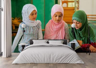 A group of children reads the holy book Quran in the mosque. Happy Muslim family. Muslim girls in hijab learning about Islam religion.	 Wall mural