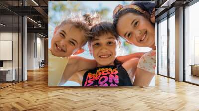 Close up face of happy children embracing each other and smiling at camera, group of joyful kids playing together outside. Wall mural