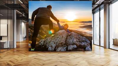 Hiking team people helping each other friend giving a helping hand while climbing up on the mountain rock adventure travel concept of support trust teamwork success. Wall mural