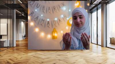 Muslim woman praying with hands up during the holy month Ramadan. Wall mural