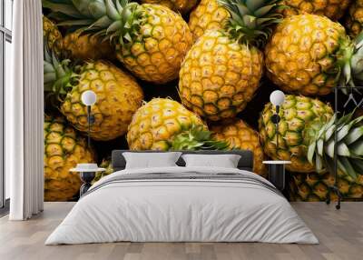 Freshly cut pineapples arranged tightly, showcasing the bright yellow fruit and spiky green tops Wall mural