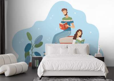 Young man and woman reading while sitting on stack of big books Wall mural