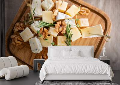 Cheese plate. Delicious cheese mix with walnuts, honey on wooden table. Tasting dish on a wooden plate. Food for wine. Wall mural