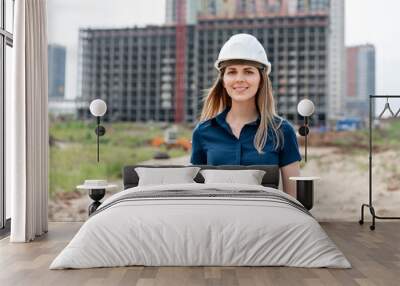 Female construction engineer. Architect with a tablet computer at a construction site. Young Woman look in camera, building site place on background. Construction concept Wall mural