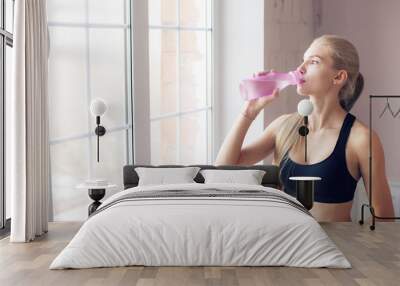 home fitness. drink clean water from a bottle. Lovely young blonde girl. near the window Wall mural