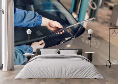 Technician is changing windscreen wipers on a car station. Wall mural