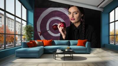 Sinister young woman with red apple standing near target Wall mural