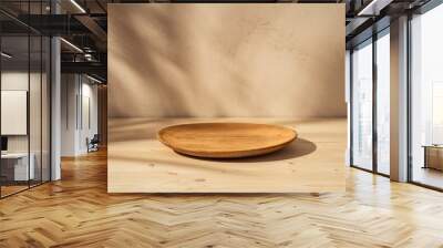 Wooden plate or bowl on wooden table on stucco background with branch shadow on the wall. Mock up for branding products, presentation and health care. Wall mural