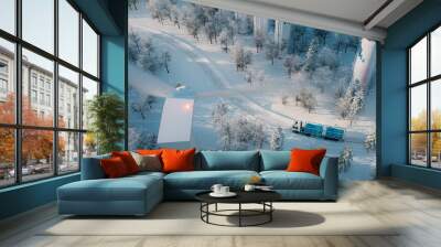 A truck with a hydrogen filling device, hydrogen storage tanks and a wind farm captured from a bird's eye view in the middle of a snowy forest. 3D rendering Wall mural