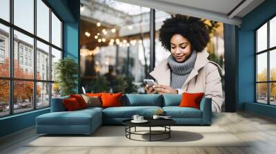 Young woman using smartphone for online shopping in a coffee shop Wall mural