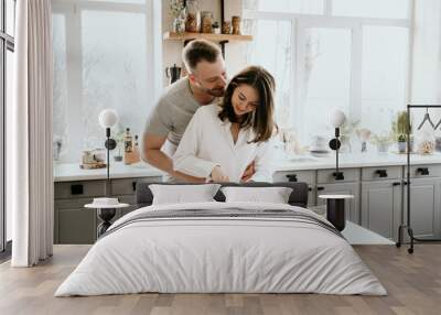 Romantic young couple cooking together in the kitchen,having a great time together. Wall mural