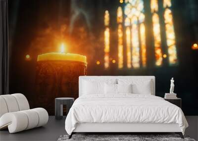 A lit candle in a church with a stained glass window in the background. Wall mural