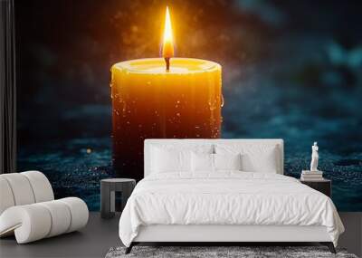 A single candle burning brightly in the dark, surrounded by water droplets. Wall mural