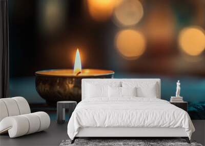 A single candle flame glows brightly in a dimly lit room, symbolizing hope and peace. Wall mural