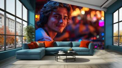 A young man smiles at the camera while mixing music at a party. Wall mural