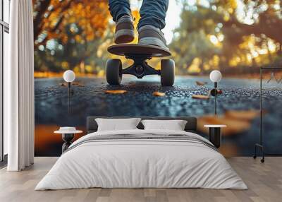 Close-up of feet on a skateboard rolling on an asphalt path with fallen leaves. Wall mural