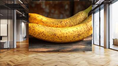 Two ripe yellow bananas with brown spots on a wooden table. Wall mural