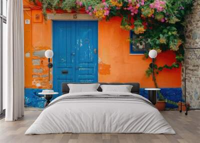 A colorful exterior of a house with a blue door, orange wall, and a window, set on a stone paved street concept of vibrant home architecture Wall mural