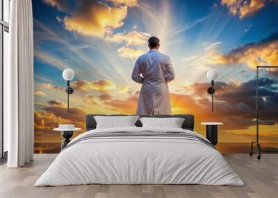 A serene healthcare professional in a white coat stands with arms crossed, silhouetted against a breathtaking vibrant sunrise, symbolizing hope and new beginnings. Wall mural