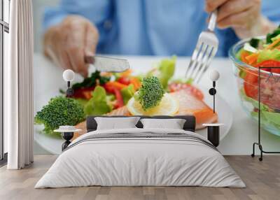 Asian elderly woman patient eating salmon stake and vegetable salad for healthy food in hospital. Wall mural