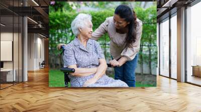 Caregiver help Asian elderly woman disability patient sitting on wheelchair in park, medical concept. Wall mural