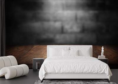 Old wood table with blurred concrete block wall in dark room background. Wall mural