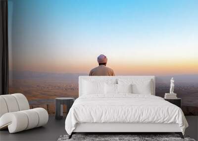 man sitting in meditation pose overlooking city at sunset Wall mural