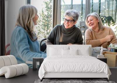 Group of elderly women have breakfast in a cafeteria, three retired female friends are celebrating an anniversary drinking tea and coffee and eating chocolate cakes Wall mural