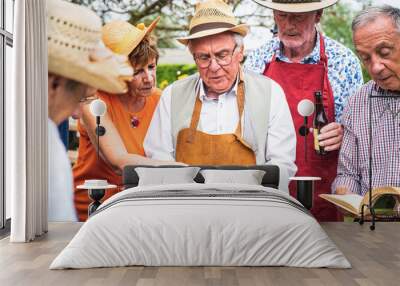 Group of senior people at a family party while reading songs and books, preparing a lunch and an outdoor party in the garden, concept of healthy and happy old age Wall mural