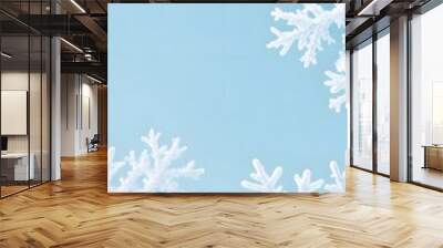 A serene winter background featuring delicate snowflakes on a soft blue backdrop, creating a tranquil and festive atmosphere. Wall mural