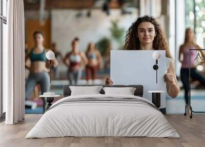 A woman is holding a white sign in a yoga class Wall mural