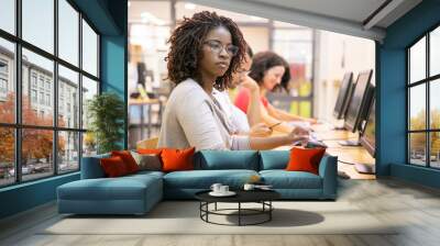 African American adult student working in computer class. Line of man and women in casual sitting at table, using desktops, typing. Staff training concept Wall mural