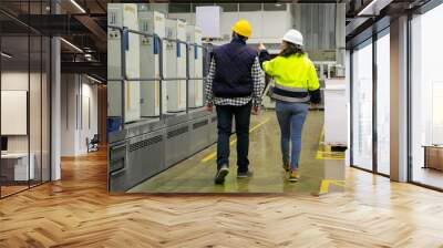 Back view of two factory employees walking near printing machine. Rear view of woman pointing at printing press. Print manufacturing concept Wall mural