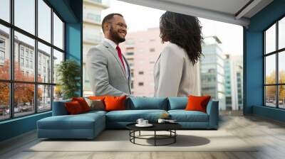 Business colleagues greeting each other near office building. Business man and woman shaking hands with each other outside in city. Cooperation concept Wall mural