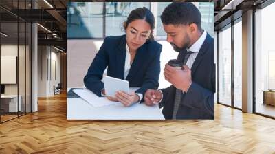 Business people using tablet computer at cafe table. Business man and woman wearing formal clothes, sitting and drinking coffee. Partnership concept. Front view. Wall mural