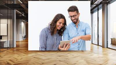 Cheerful couple watching content on tablet and laughing. Young woman in casual and man in glasses in glasses posing isolated over white background. Internet service concept Wall mural