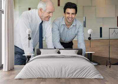 Cheerful entrepreneur showing application to colleague. Smiling businessmen discussing information on tablet computer at meeting. Successful work concept Wall mural