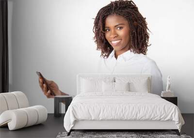 Cheerful happy sales manager using corporate mobile app, looking at camera. Young African American business woman standing isolated over white background. Smartphone using concept Wall mural