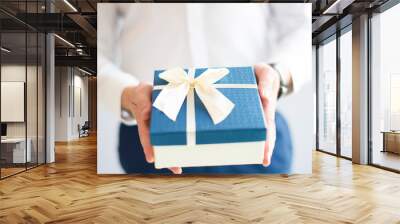 Closeup of man giving big gift box with bow. Person greeting someone. Gift concept. Isolated cropped view on grey background. Wall mural