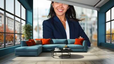 Confident cheerful young businesswoman. Professional business woman standing with crossed arms and smiling at camera inside office building. Business concept Wall mural