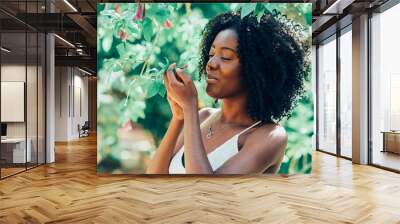 Content Black Woman Smelling Flowers in Park Wall mural