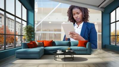 Focused professional using app on tablet outside. Young African American business woman holding digital device, looking at screen, smiling. Online app concept Wall mural