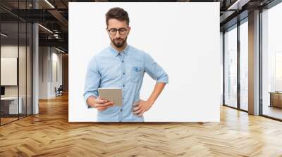 Focused tablet user reading content on screen. Handsome young man in casual shirt and glasses standing isolated over white background. Wireless internet technology concept Wall mural