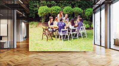 Friends in sportswear eating outdoors. Sporty young male and female friends gathering around table and eating healthy dishes in backyard. Healthy lifestyle concept Wall mural