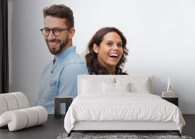 Happy cheerful couple leaning on each other, laughing and looking at camera. Young woman in casual and man in glasses in glasses posing isolated over white background. Close friendship concept Wall mural