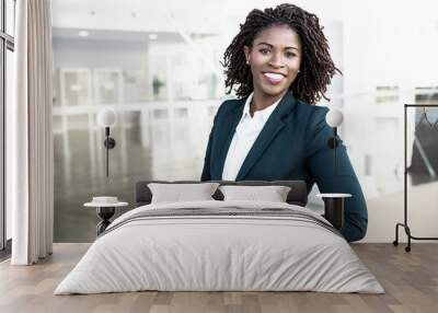 Happy confident professional posing near office building. Young African American business woman standing outside, adjusting formal jacket, looking at camera, smiling. Successful businesswoman concept Wall mural