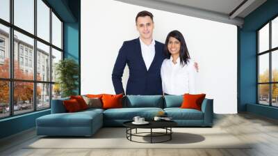 Happy couple of employees wearing office clothes. Positive young Caucasian man in trendy jacket hugging his Indian girlfriend in white blouse. Colleagues dating concept Wall mural